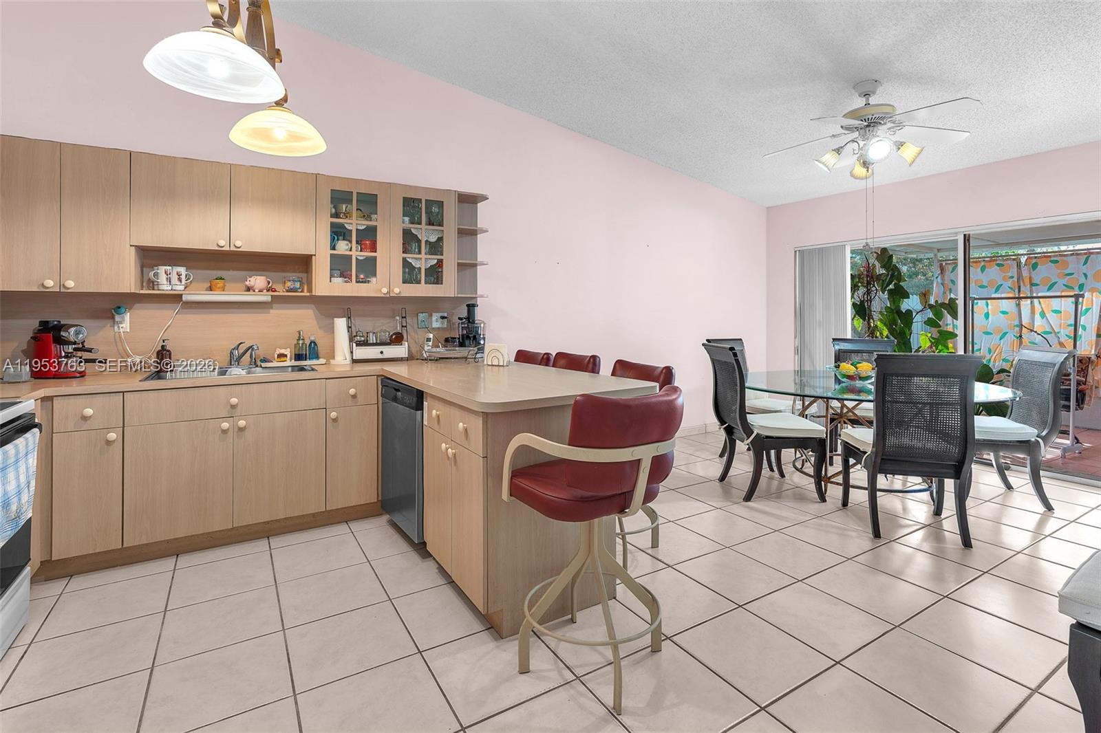 1002 Southwest 142nd Court Miami, FL 33184 - Photo 7 of 50 a kitchen that has a sink a stove a dining table and chairs with white cabinets