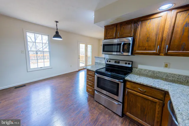 a kitchen with granite countertop wooden cabinets stainless steel appliances and a window