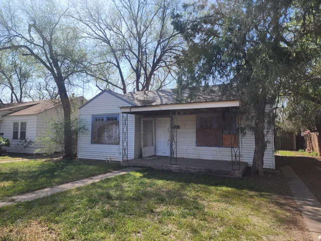 a view of a house with a yard and large tree