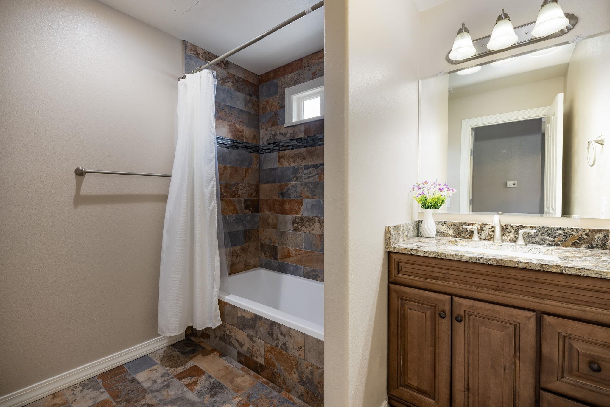 1168 Windsor Park Drive Fruita, CO 81521 - Photo 33 of 41 a bathroom with a granite countertop sink a mirror and a bathtub
