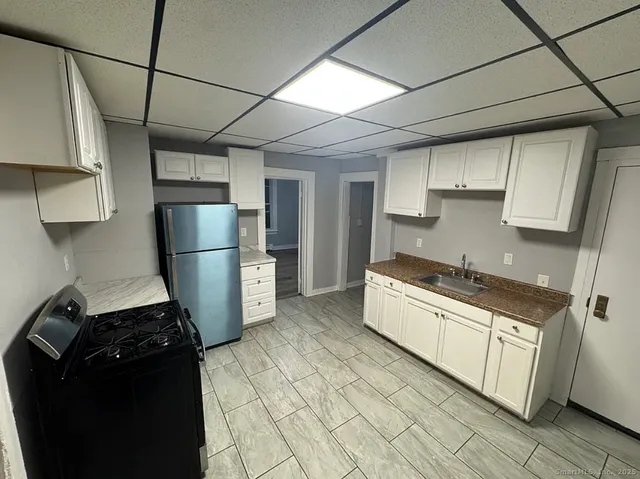a kitchen with stainless steel appliances granite countertop a refrigerator a stove and a sink
