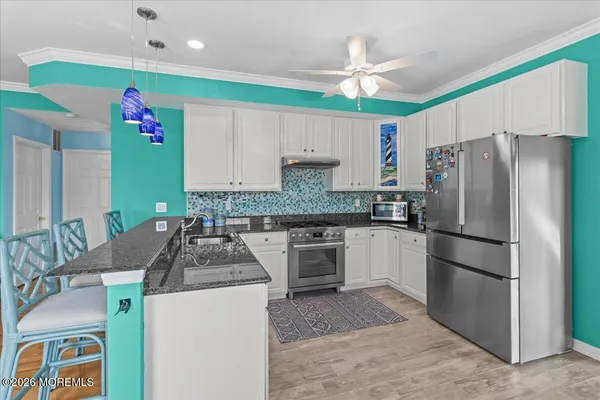 a kitchen with kitchen island granite countertop a sink stainless steel appliances and a chandelier