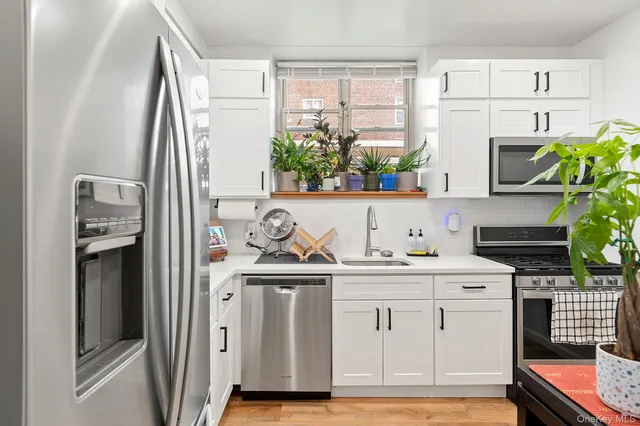 a kitchen with stainless steel appliances granite countertop a stove a refrigerator and a white cabinets
