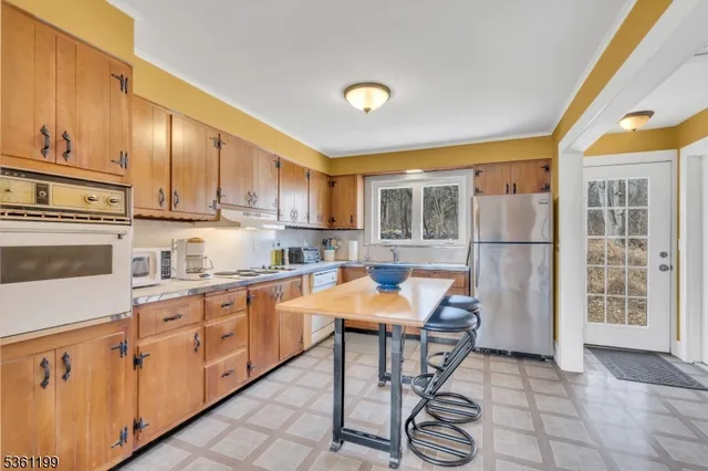 a kitchen with stainless steel appliances granite countertop a refrigerator and wooden cabinets