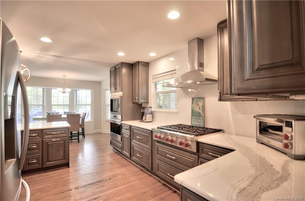 20210 Bascom Ridge Drive Cornelius, NC 28031 - Photo 5 of 35 a kitchen with stainless steel appliances granite countertop a stove top oven a sink dishwasher and white cabinets with wooden floor
