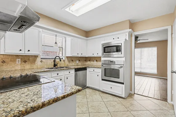 a kitchen with granite countertop white cabinets and white appliances