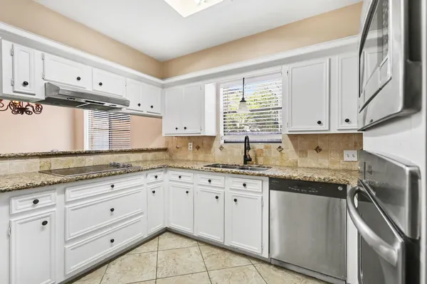 a kitchen with granite countertop cabinets stainless steel appliances and wooden floor