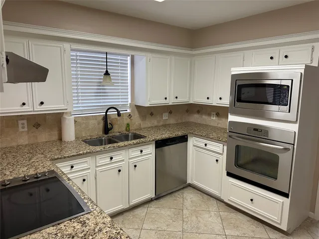 a kitchen with granite countertop white cabinets stainless steel appliances and a window