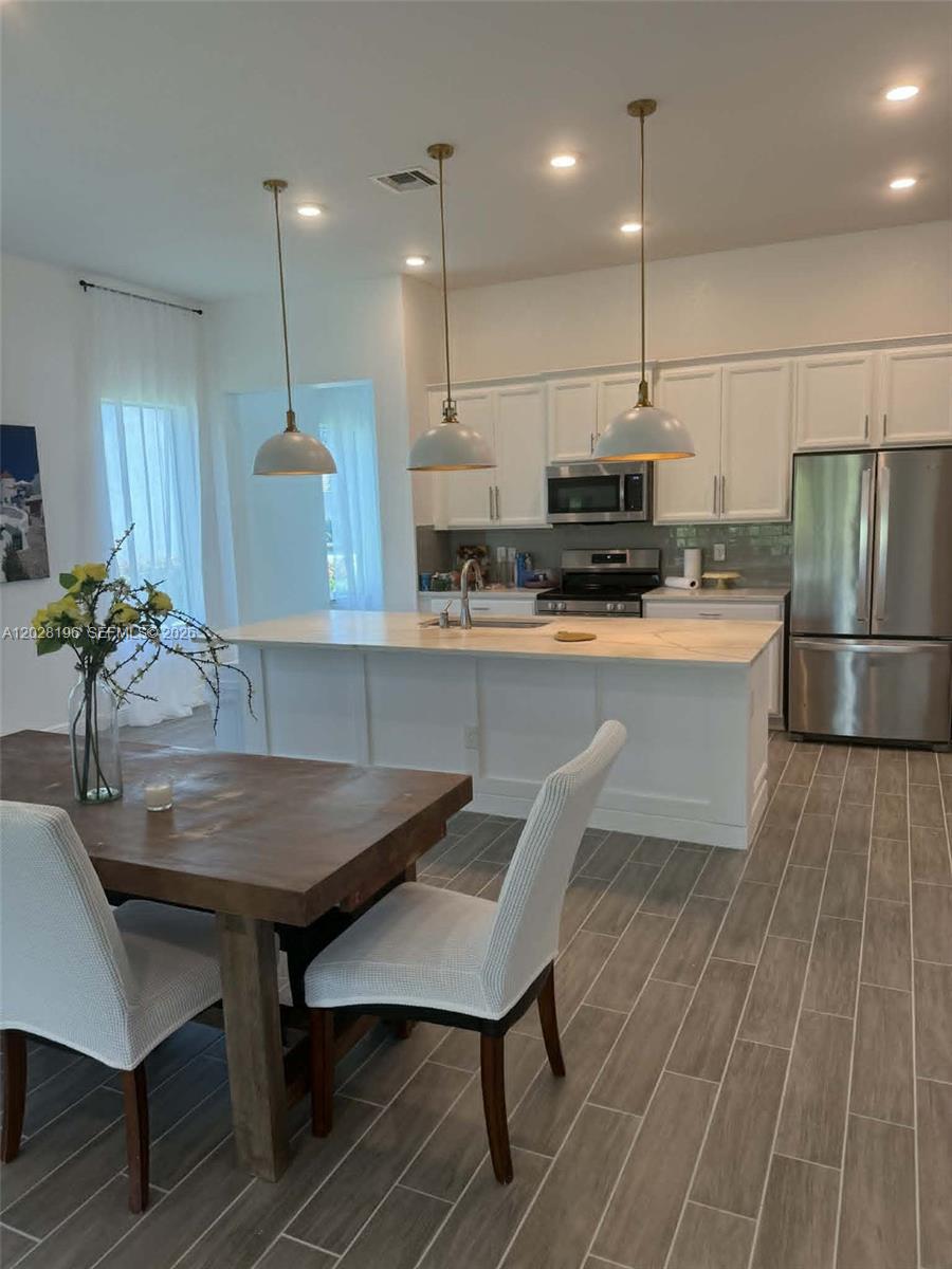4710 Southwest Ardsley Drive Stuart, FL 34997 - Photo 2 of 7 a kitchen with kitchen island a table and chairs in it