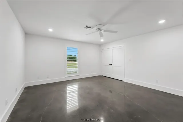 an empty room with windows and ceiling fan