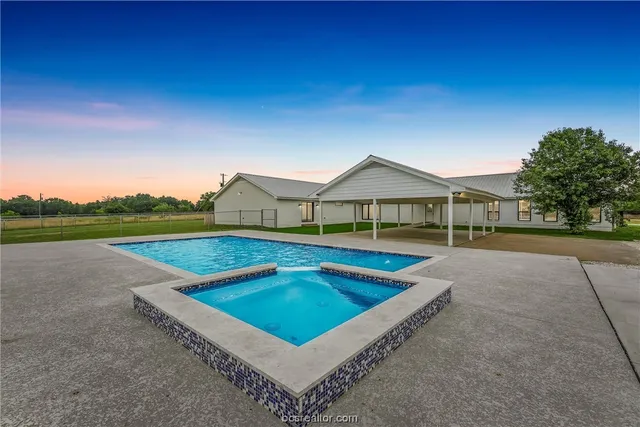 a view of swimming pool with seating area and trees in the background