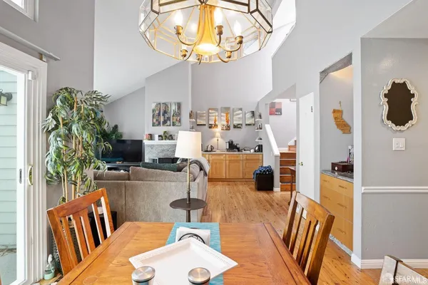 a living room with furniture a chandelier and a dining table with wooden floor