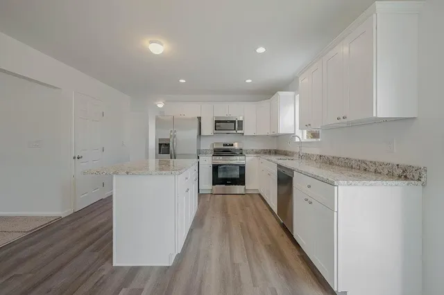 a kitchen with granite countertop white cabinets and stainless steel appliances