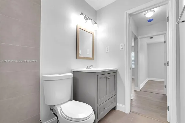 a bathroom with a toilet sink vanity and mirror