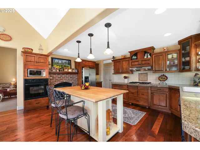 a kitchen with stainless steel appliances kitchen island granite countertop a table chairs and a refrigerator