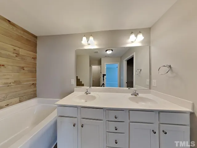 a bathroom with a double vanity sink mirror and bathtub
