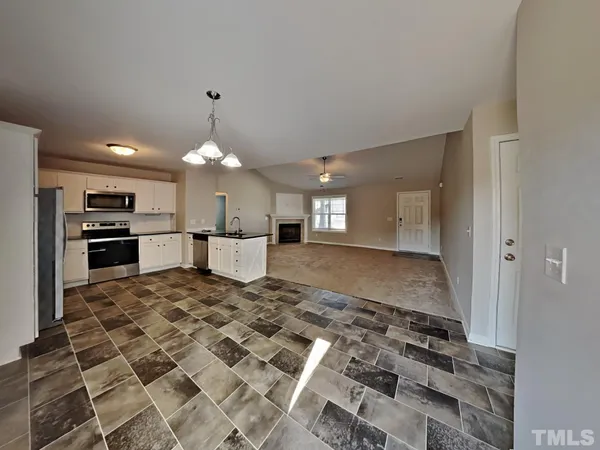 a large kitchen with kitchen island granite countertop a refrigerator and a stove top oven