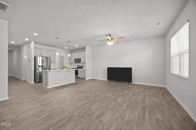 a view of a livingroom with a kitchen stove and wooden floor