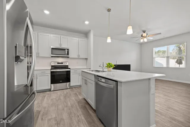 a kitchen with kitchen island a counter top space stainless steel appliances and a window