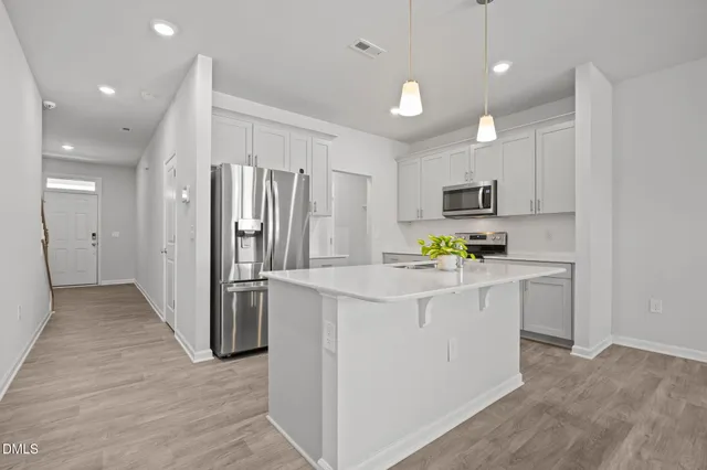 a kitchen that has a lot of white cabinets and stainless steel appliances