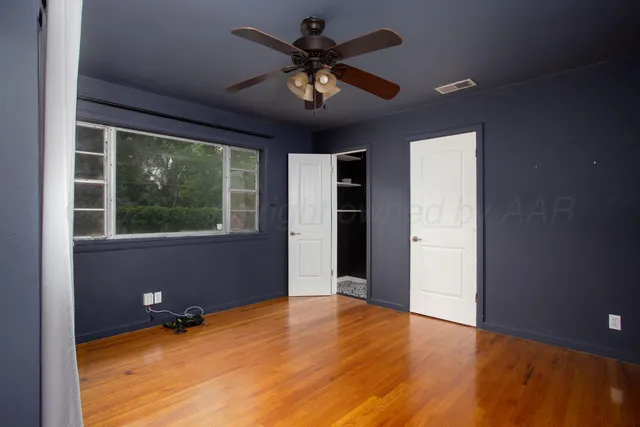 an empty room with a window and a ceiling fan