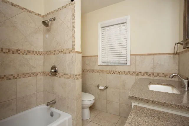 a bathroom with a granite countertop bathtub shower sink and toilet