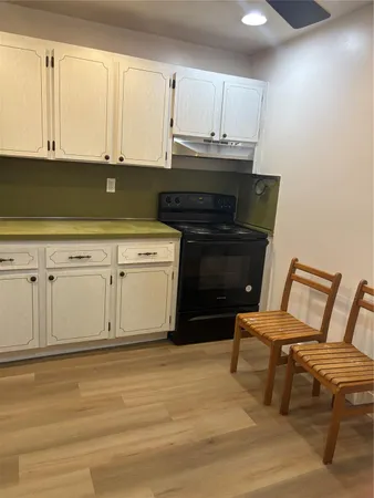 a kitchen with a stove chair and white cabinets