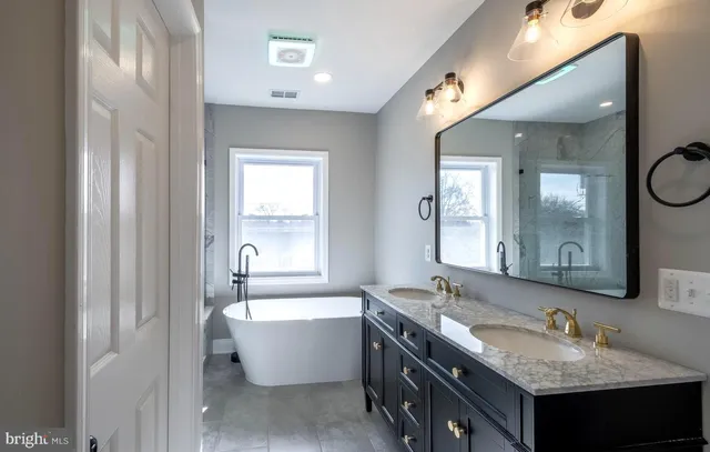 a bathroom with a granite countertop tub sink and mirror
