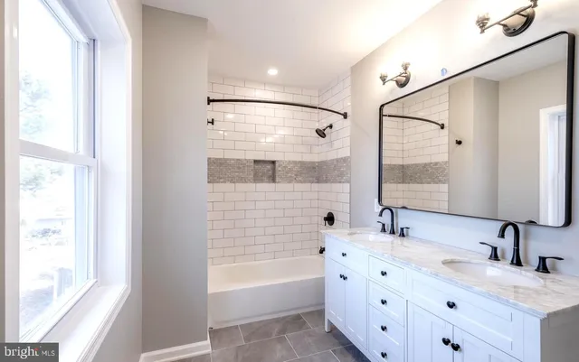 a bathroom with a double vanity sink double mirror and bathtub