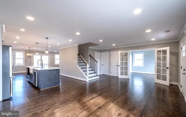 a view of an empty room with wooden floor and windows