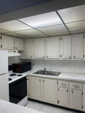 a kitchen with granite countertop a sink dishwasher a stove and cabinets with wooden floor