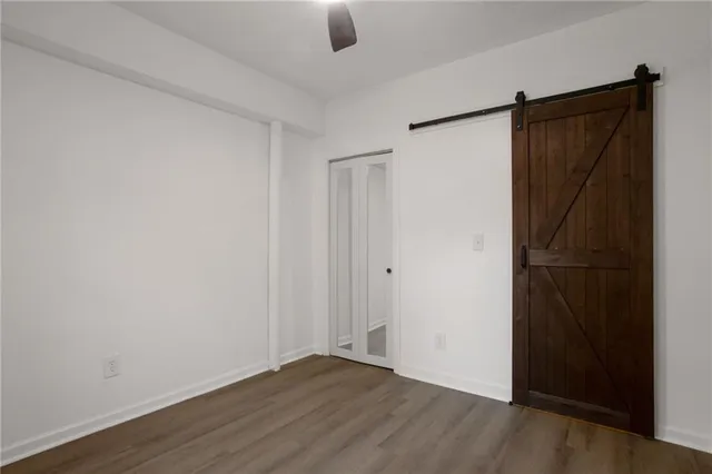 a view of an empty room with wooden floor and closet