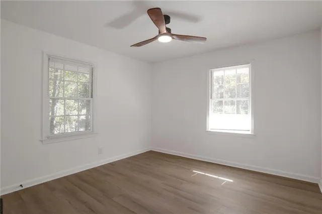 a view of an empty room with wooden floor and a window