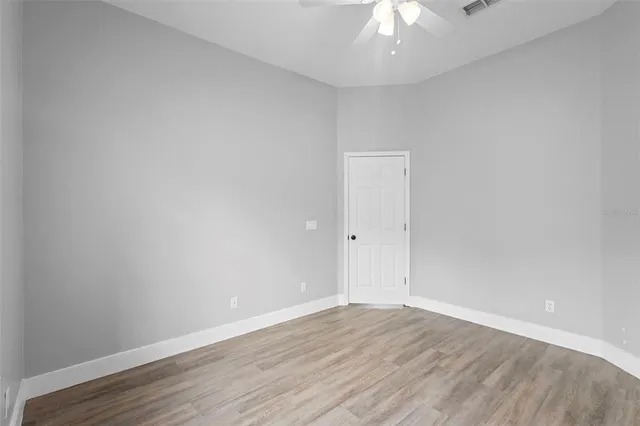 a view of empty room with wooden floor and fan