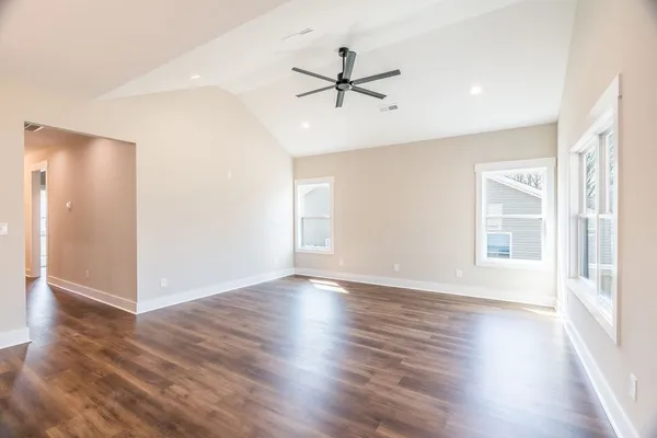 an empty room with wooden floor fan and windows