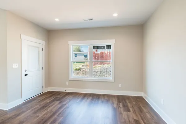 an empty room with wooden floor and windows