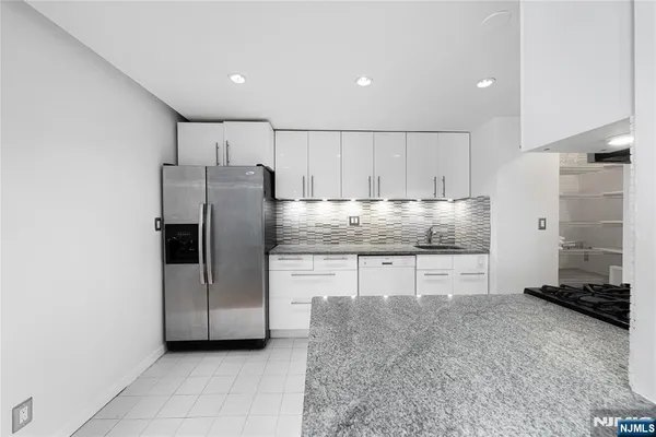 a kitchen with granite countertop a refrigerator and a sink