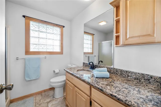 a bathroom with a granite countertop sink a toilet and a mirror