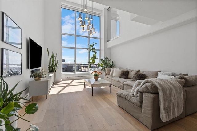 a living room with furniture a flat screen tv and a floor to ceiling window