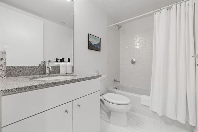 a bathroom with a granite countertop sink a toilet and shower
