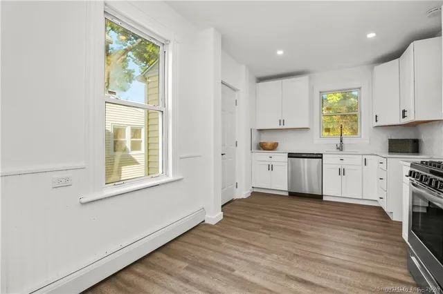 a kitchen with granite countertop a refrigerator stove and wooden floor