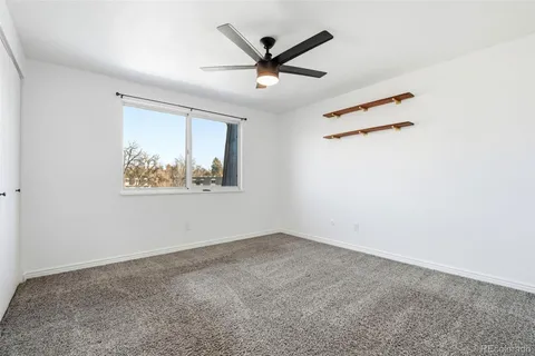 an empty room with ceiling fan and window