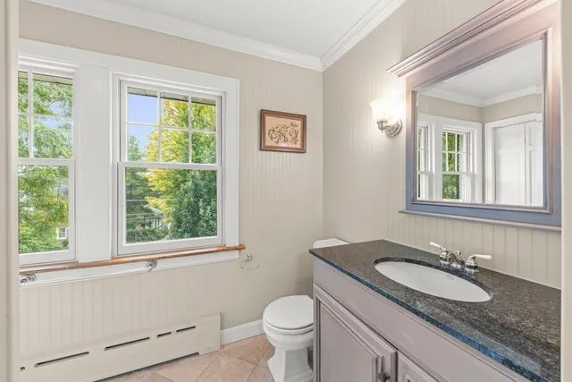 a bathroom with a granite countertop toilet a sink and a window