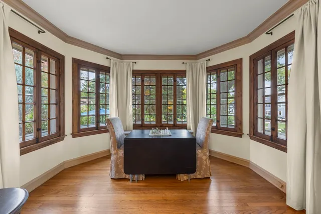 a dining room with wooden floor and windows