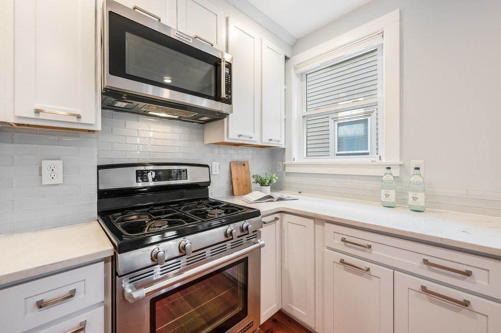 44 Roberts Road, Unit 2 Cambridge, MA 02138 - Photo 12 of 36 a kitchen with stainless steel appliances granite countertop a sink a stove a microwave and wooden cabinets