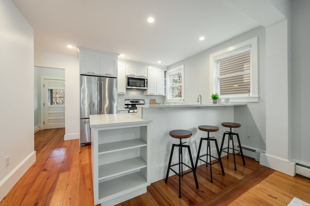 44 Roberts Road, Unit 2 Cambridge, MA 02138 - Photo 9 of 36 a kitchen with stainless steel appliances a dining table chairs and a refrigerator