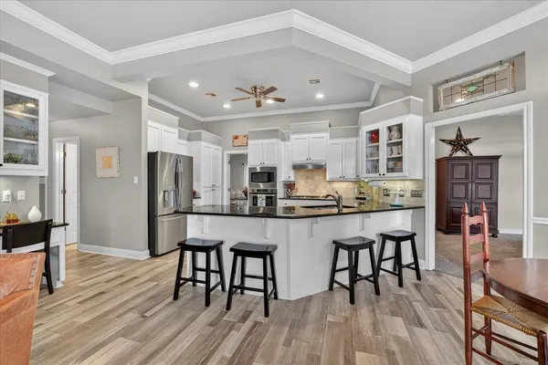 a kitchen with stainless steel appliances kitchen island granite countertop a table chairs and a refrigerator