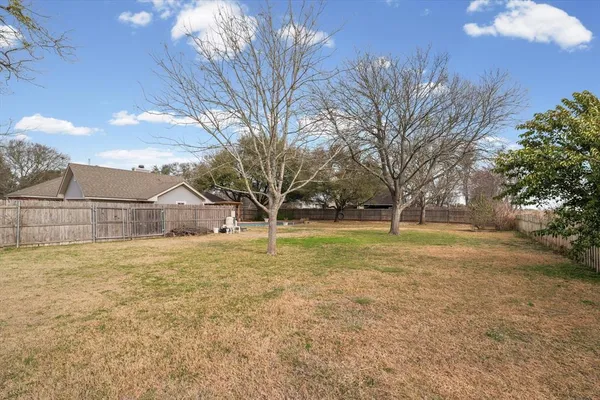 a view of a yard in front of a house with large trees