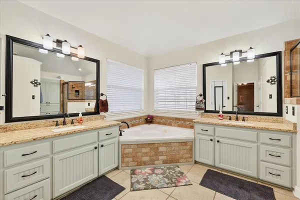 a bathroom with a sink double vanity granite and a bathtub