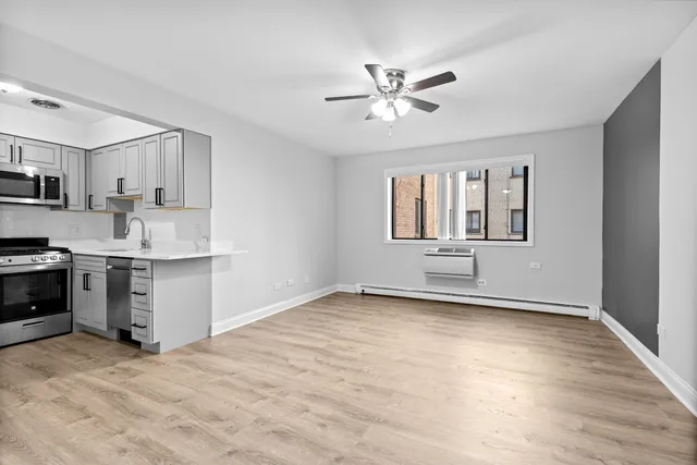 a view of a kitchen with a sink and dishwasher a stove top oven with wooden floor